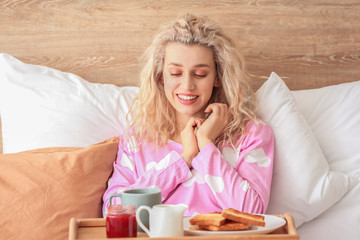 Morning of beautiful young woman having breakfast in bed