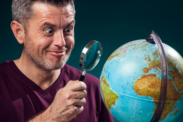 A man in t-short holding globe and magnifier. Travel and education concept