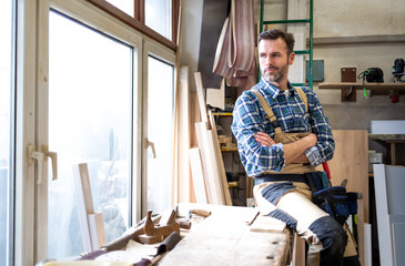 Smiling and proud mature carpenter in his carpentry workshop