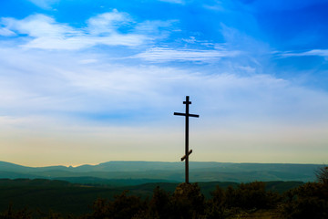 Black religion symbol silhouette Jesus Christ wooden cross on a background with colorful mountain sunset, Easter concept.
