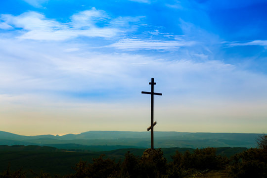 Black religion symbol silhouette Jesus Christ wooden cross on a background with colorful mountain sunset, Easter concept.