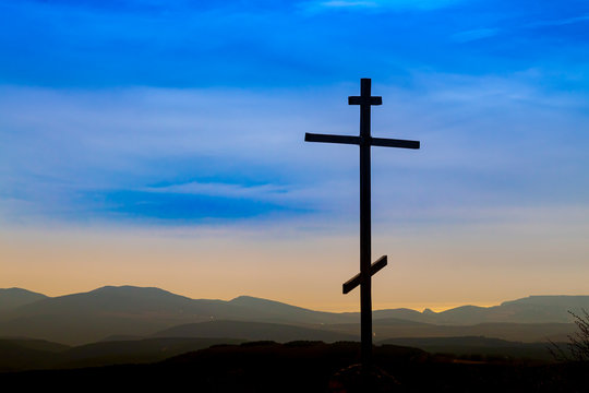 Black religion symbol silhouette Jesus Christ wooden cross on a background with colorful mountain sunset, Easter concept.