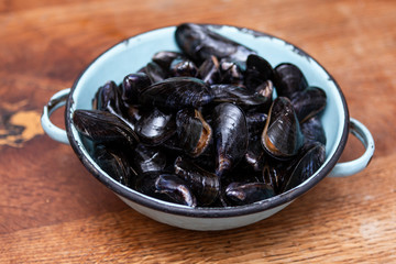 Raw mussels in a blue colander