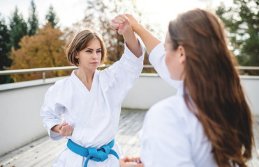 Young women practising karate outdoors on terrace.
