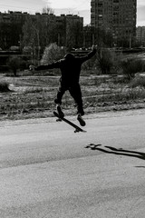 Teenager man on skateboard practicing at the park making jump and perform stunts  in spring autumn in motion in black and white picture. Sport extreme concept