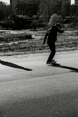 Teenager man on skateboard practicing at the park making jump and perform stunts  in spring autumn in motion in black and white picture. Sport extreme concept