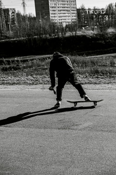 Teenager man on skateboard practicing at the park making jump and perform stunts  in spring autumn in motion in black and white picture. Sport extreme concept