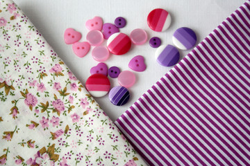 Natural fabric with a pattern and buttons for sewing clothes. View from above. There is a free space. A set of fabric for needlework.