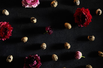 Quail eggs and moody flowers on old dark background