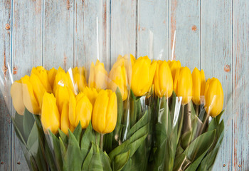 Background with flowers. Tulips in a bouquet white and yellow on a wooden blue background. Gifts for International Women's Day, birthday, mother's day. Greeting card with flowers and place for text.