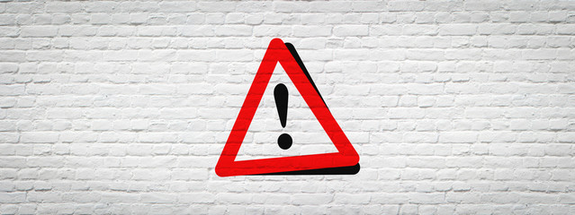 Warning sign on white brick wall