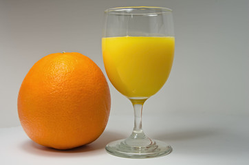 Fresh orange and glass of newly squeezed orange juice.