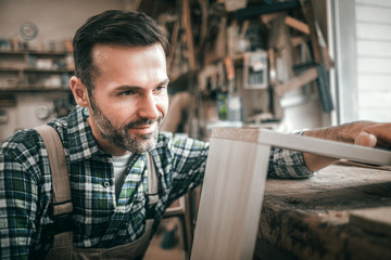 Craftsman at workshop working at wooden shelf