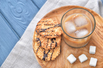 Glass of tasty iced coffee with cookies on table