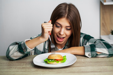 Obraz na płótnie Canvas Nice girl wants to eat hamburger harmful