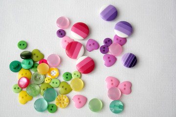 many bright, multi-colored, plastic buttons on a white background