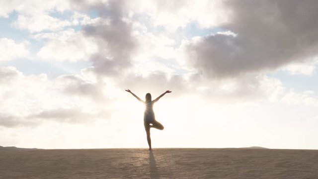 SLOW MOTION Silhouette of female model moving hands in balanced yoga one legged pose. Amazing balance and meditation. Sun salutation yoga.
