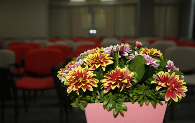 Flowers composition on table in empty conference room, office.