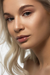 Fototapeta premium Closeup portrait of a woman with developing straight hair. Sweet tender young girl blonde. Natural lipstick, transparent clean skin. Skin care natural cosmetics in the spa salon or cosmetology.