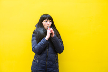 Vape teenager. Young pretty white caucasian brunette girl with blue eyes and in a blue jacket...