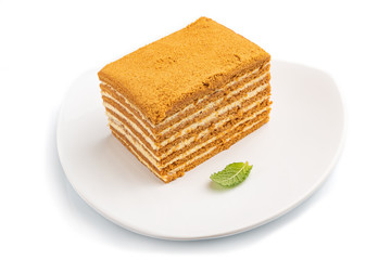 Homemade honey cake with milk cream and mint isolated on white background. Side view.