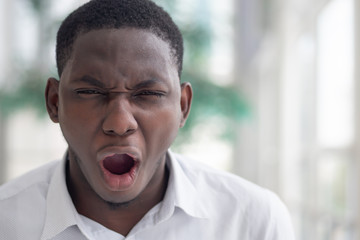 angry frustrated black African businessman, worker, employee shouting out loud with very serious emotion expression