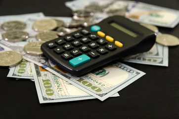 dollars, coins and calculator on a black background. Business concept.