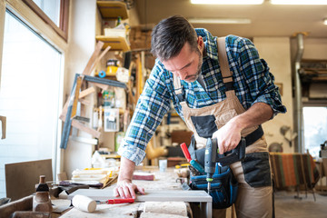 Carpenter using woodworking tools for craft work in carpentry workshop