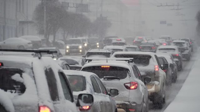 City road traffic jam moving in winter snowfall, strong blizzard