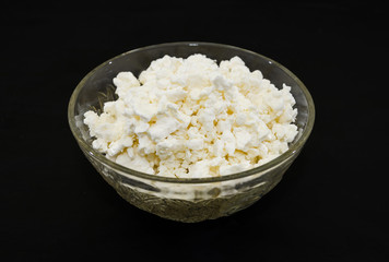 cottage cheese in a plate on a black background.