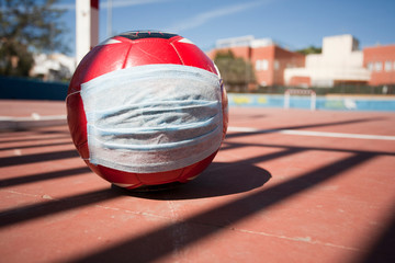 Soccer and coronavirus concept, soccer ball with respiratory mask on soccer field closed to the public, space to write