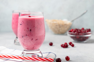 Two glasses with freshly homemade smoothie of yogurt, oatmeal and cranberries on a gray table. Healthy eating concept