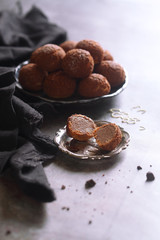 Chocolate Choux Pastry Puffs with Craquelin, powdered with icing sugar, on a plate, on grey background.