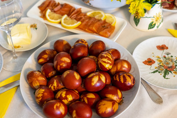 Easter table with large plate of coloured eggs. Traditional eggs dyed naturally with onion shells. Easter ecological concept.