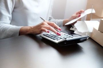 Asian woman hold receipt, bill, order note and press calculator with feeling stress, unhappy, worry or stress about the calculate of prepare money for payment to purchase the goods, product shipping