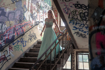 junge Frau schreitet im Balkleid im Lost Place eine Treppe herunter