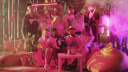 Attractive and stylish boys and girls enjoying hangout dancing into music in cool neon-lighted colorful nightclub. Party celebration. Communication concept.