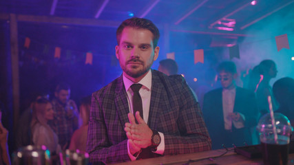 Indoor portrait of attractive guy businessman in suit with charming smile staying at bar counter in...