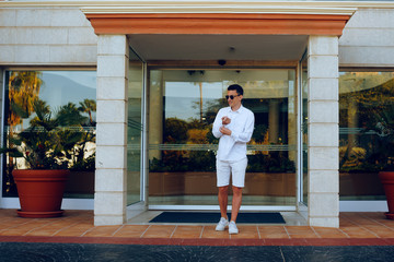 A man dressed in white, leaves the hotel on vacation. Men leaves the hotel, owner. Young businessman on vacation. A man goes on a date. Man with glasses. Rest alone. The traveler.