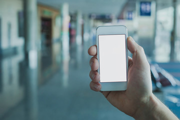 hand holding smartphone with empty blank screen in airport, mobile app for travel