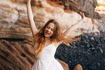 Obraz premium Gorgeous girl in a long white dress on the ocean at the beach. The model is inherited by nature laughing, having fun, going crazy. Happy girl on vacation, summer, emotions. The bride on vacation.