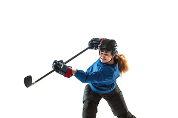 Young female hockey player with the stick on ice court and white background. Sportswoman wearing equipment and helmet training. Concept of sport, healthy lifestyle, motion, action, human emotions.