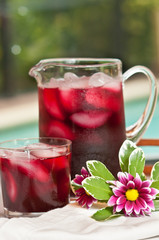 Front view, close distance of a glass pitcher and two glasses of raspberry punch, served at pool side of a luxury hotel
