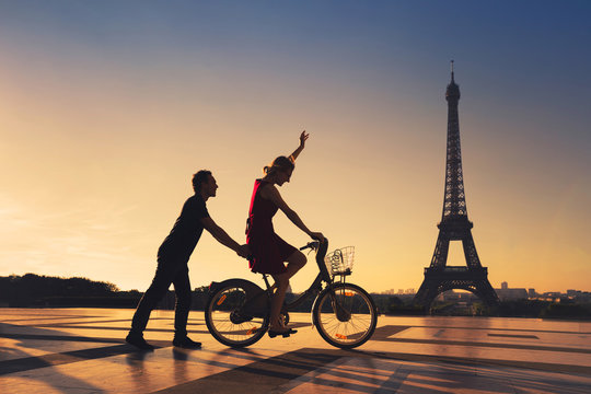 happy couple having fun in Paris riding bicycle near Eiffel tower, silhouettes