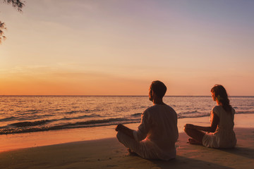 meditation and relaxation for couple, yoga group on the beach at sunset