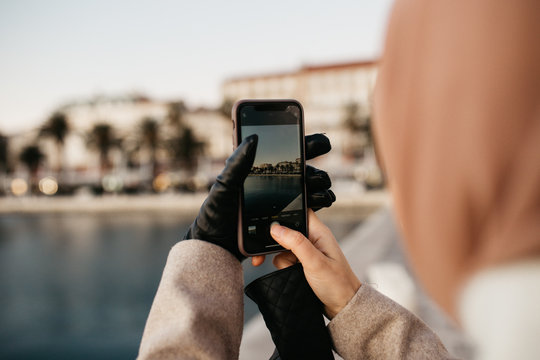 Close up photo of female hands holding mobile phone and taking photos of beautiful city of Split, Croatia. 