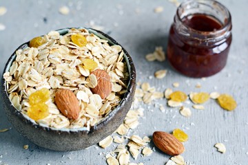 Home granola in a bowl. Selective focus. Healthy vegan snack. Granoll morning breakfast with almonds, raisins, dried cranberries on a blue (gray) background. Healthy eating concept