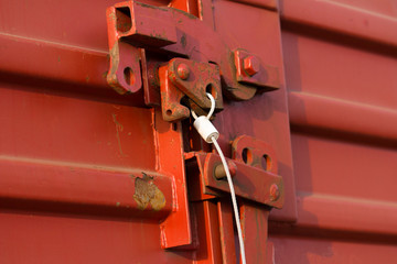 Red railway freight car with The lock on a door with a metal seal.