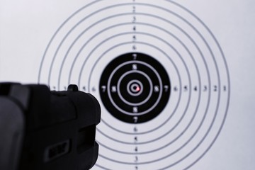 Background with a pistol aimed at a round target with a red dot from a laser sight in the center....