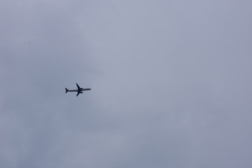 Gray plane in flight with gray cloudy background